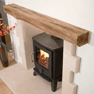 Timber effect beam mantel above a wood-burning stove in a recessed fireplace