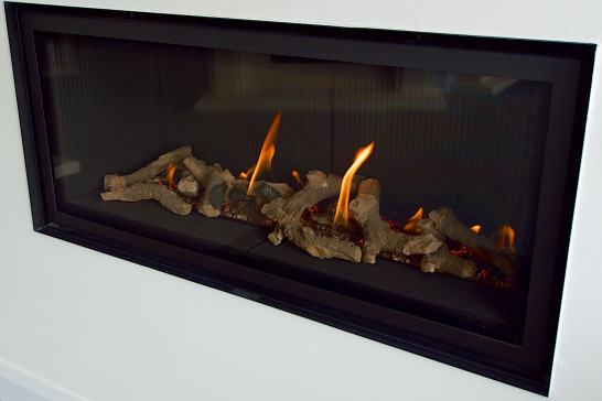 Close-up of a Gazco Studio 2 wide gas fire with driftwood log-effect fuel bed